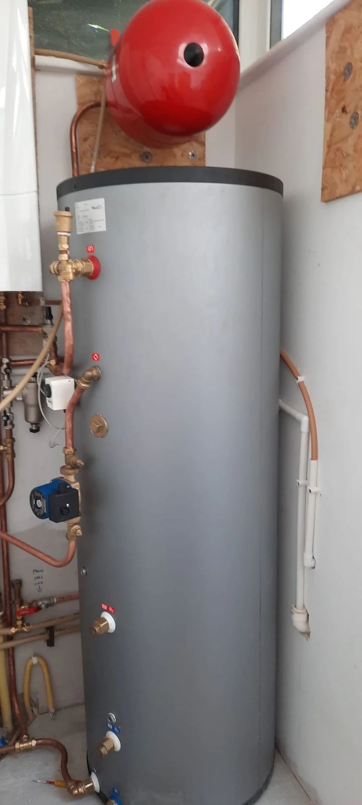 Grey hot water cylinder fitted with a red expansion vessel